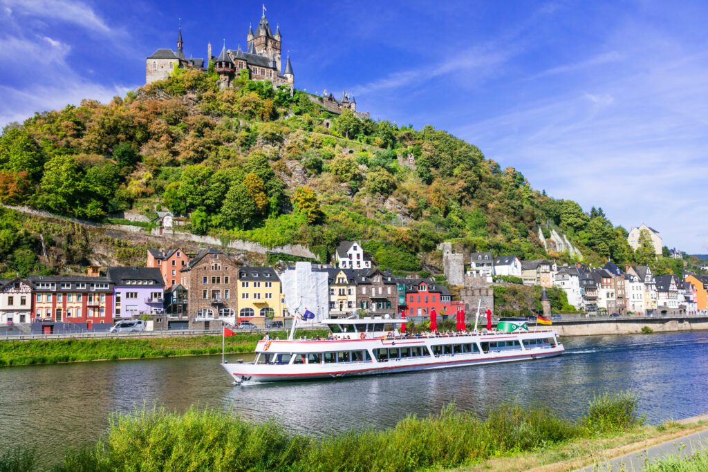 A cruise boat on the Mosel river with the Reichsburg of Cochem in the background