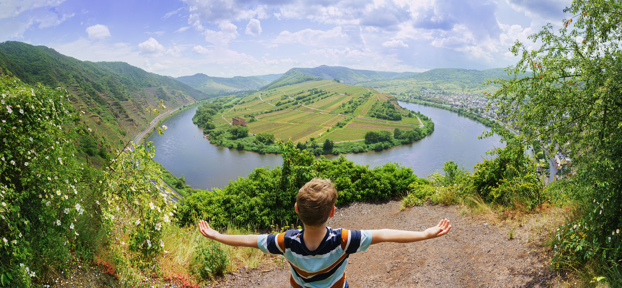 boy on top of a hill overlooking the Mosel river, strechting his arms out to an embrace