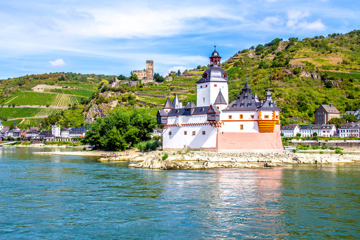 small white castle resembling a ship sanding in the currents of the Rhine River