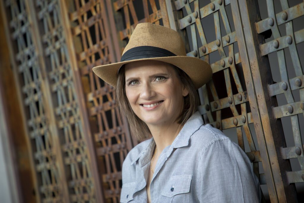 picture of Eva Metz-Tolliver, founder of Germany Travel Co., wearing a blue collard shirt and a hat, smiling into the camera