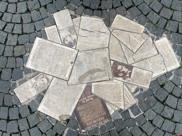 A bunch of flowers arranged in a circles and sketched into the cobblestones as part of the White Rose Memorial 