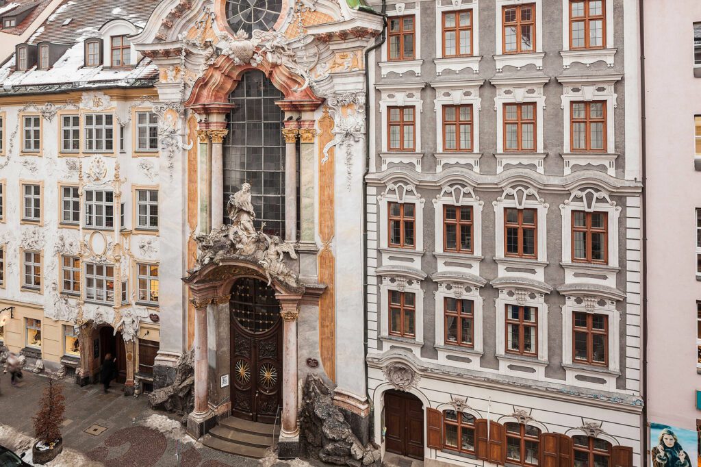 The narrow facade of Asam church in Munich, Germany is tucked in between two houses