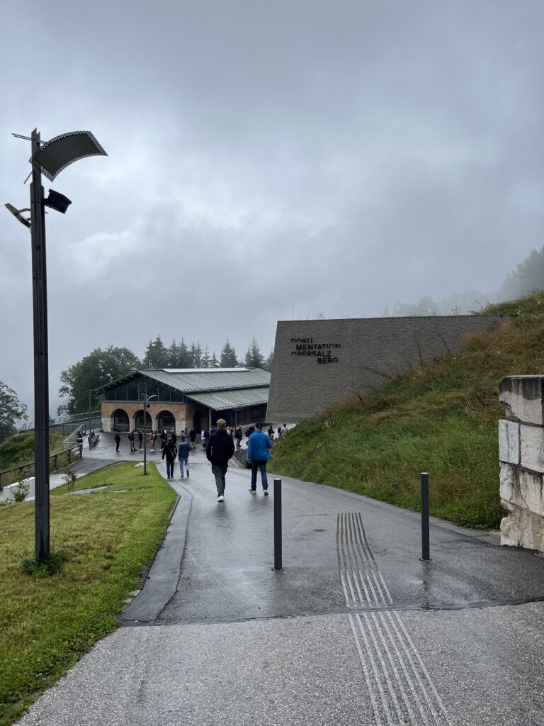 A path leading up to two structures. A sign on one of them reads: "Dokumenationszentrum Obersalzberg"