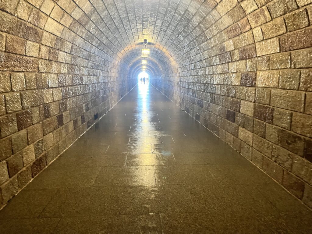 A long tunnel, light shining through from the other end, leading up to the elevator at Eagles' Nest in Berchtesgaden